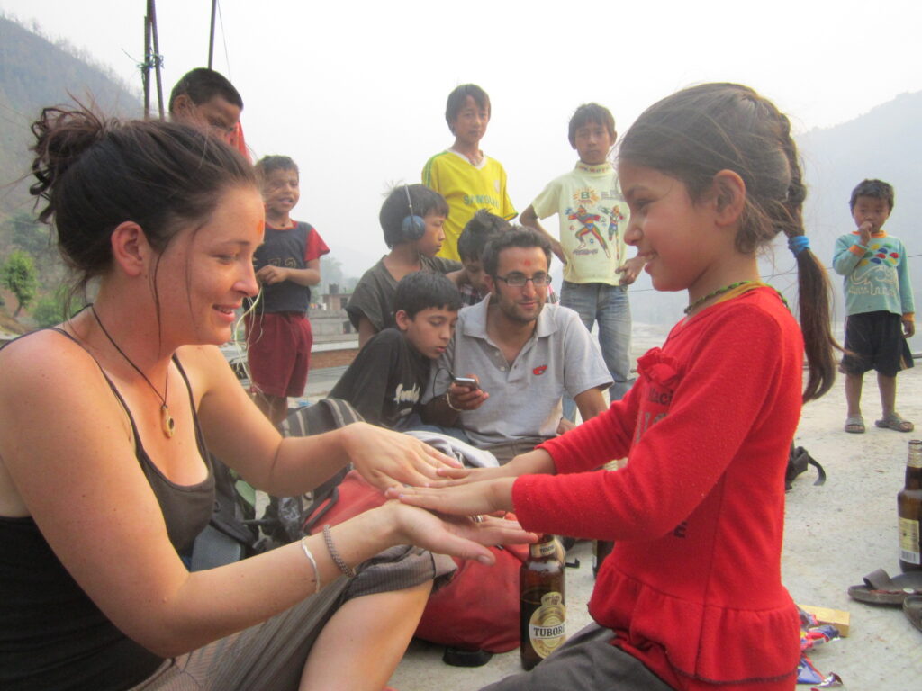 A traveler and a young girl share a playful moment while children gather around in a village in eastern Nepal.