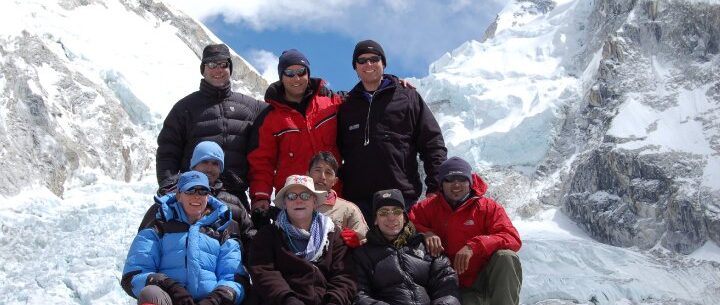 Trekking group posing together at Everest Base Camp, surrounded by the Khumbu Icefall and glacier.